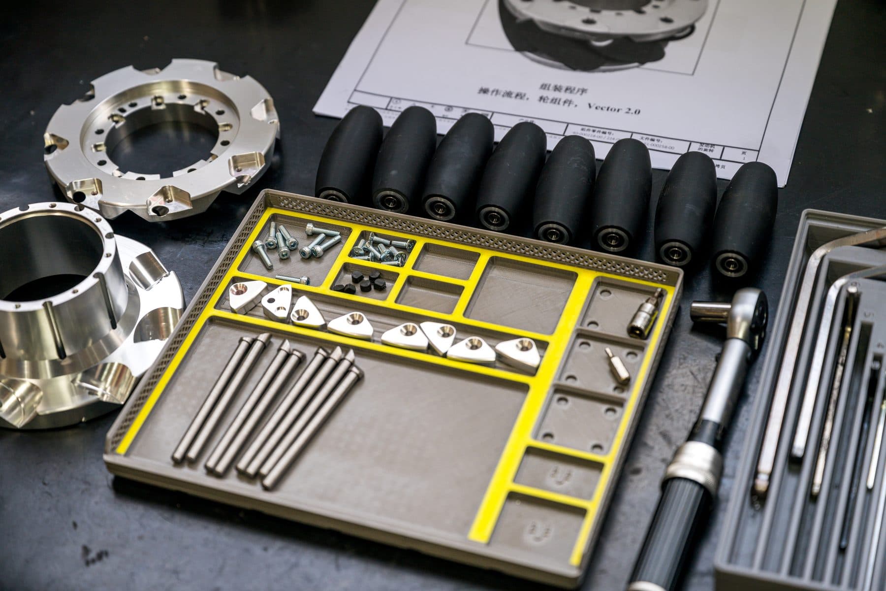 Mecanum wheel kit: machined hubs, rollers, hardware, and assembly drawing laid out on the bench